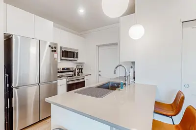 a kitchen with white cabinets and a stainless steel refrigerator at Mellow on Meadow Mile 2A in Fraser
