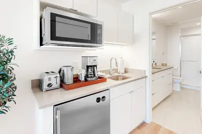 a white kitchen with a microwave above a sink at Mellow on Meadow Mile 2B in Fraser