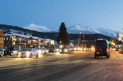 a busy city street with cars at night with snow covered mountains at Antler Way at Lakota,,,, townhouse in Winter Park