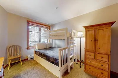 a bedroom with bunk beds and a desk and a dresser at Mountainside Majesty in Keystone
