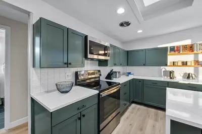 a kitchen with green cabinets and white counter tops at Lunceford - Northglenn in Northglenn