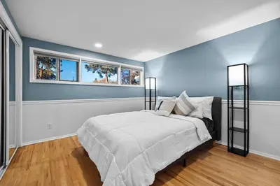 a blue bedroom with a bed and two windows at Lunceford - Northglenn in Northglenn