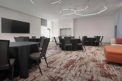 a conference room with tables and chairs and a screen at Hilton Garden Inn Denver Airport Tower Road in Denver