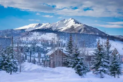 a snow covered mountain with a house and trees at La Rive Del Lago 302 in Dillon