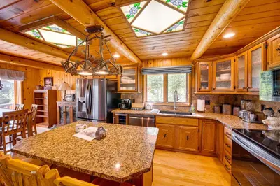 a kitchen with wooden cabinets and a large island at Lake and Mtn Views Spectacular Grand Lake Home in Grand Lake