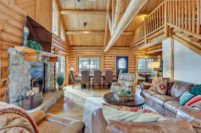 a living room with leather furniture and a stone fireplace at 4 Mi to Rocky Mtn Natl Park Cabin Near Town! in Grand Lake