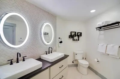 a white bathroom with two sinks and a mirror at Winter Park Condo with Hot Tub, Balcony and Shuttle! in Winter Park