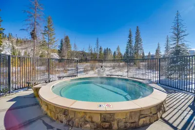 a hot tub in a patio with a fence at Winter Park Condo with Hot Tub, Balcony and Shuttle! in Winter Park