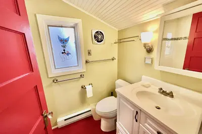 a bathroom with a toilet and a sink and a red door at Davis Cabin, Historic Charmer in Grand Lake
