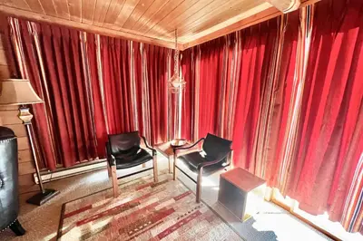 a living room with red curtains and two chairs at Davis Cabin, Historic Charmer in Grand Lake