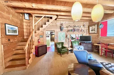 a living room with a staircase in a log cabin at Davis Cabin, Historic Charmer in Grand Lake
