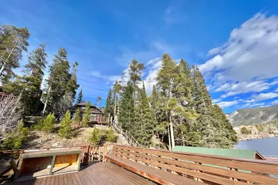 a house on a hill next to a body of water at Davis Cabin, Historic Charmer in Grand Lake