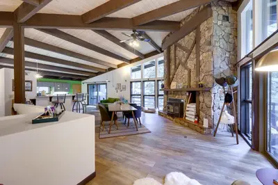 a large living room with a stone fireplace at Mid-Century Cabin Creekside, Easy Access to i-70 in Dumont