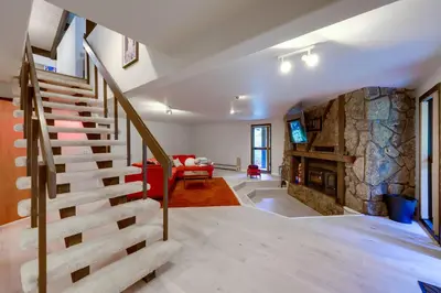 a staircase in a living room with a stone wall at Mid-Century Cabin Creekside, Easy Access to i-70 in Dumont