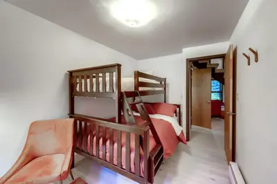 a bedroom with a bunk bed and a crib at Mid-Century Cabin Creekside, Easy Access to i-70 in Dumont