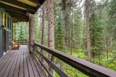 a wooden porch on a cabin in the woods at Mid-Century Cabin Creekside, Easy Access to i-70 in Dumont