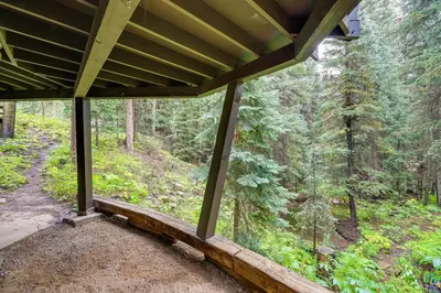 a view from the porch of a cabin in the woods at Mid-Century Cabin Creekside, Easy Access to i-70 in Dumont