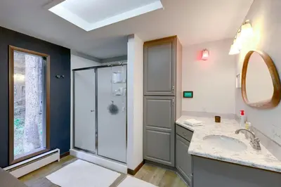 a bathroom with a shower and a sink and a mirror at Mid-Century Cabin Creekside, Easy Access to i-70 in Dumont