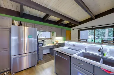 a large kitchen with a stainless steel refrigerator at Mid-Century Cabin Creekside, Easy Access to i-70 in Dumont