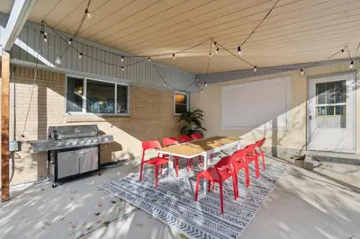 a patio with a wooden table and red chairs at NEW • Modern • 4BR • Game Rm • Ping-Pong in Arvada