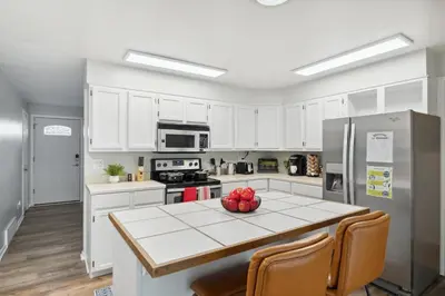 a kitchen with white cabinets and a table with fruit on it at NEW • Modern • 4BR • Game Rm • Ping-Pong in Arvada