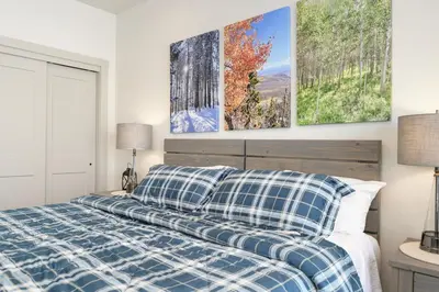 a bedroom with a blue and white bed with three paintings on the wall at Modern Granby Wonder by Leavetown Vacations in Granby