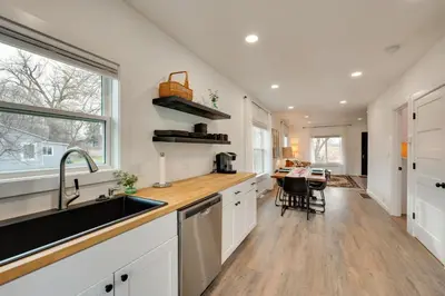 a kitchen with white cabinets and a sink and a table at Chic Erie Vacation Rental about 14 Mi to Boulder! in Erie