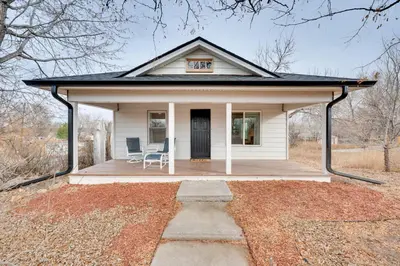 a small white house with a porch and a chair at Chic Erie Vacation Rental about 14 Mi to Boulder! in Erie