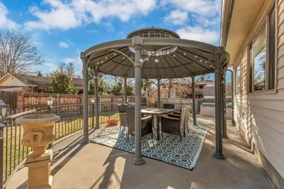 a gazebo with a table on a patio at ᨒFIREHAUSᨒHotTubᨒCinemaᨒBBQᨒBadmintonᨒGames in Arvada