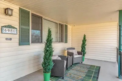 a porch with wicker chairs and trees on a house at ᨒFIREHAUSᨒHotTubᨒCinemaᨒBBQᨒBadmintonᨒGames in Arvada