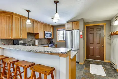 a kitchen with wooden cabinets and a counter with stools at Colorado Condo about 2 Mi to Winter Park Resort! in Winter Park
