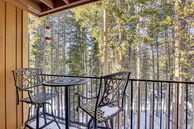a balcony with two chairs and a table with a view of the woods at Colorado Condo about 2 Mi to Winter Park Resort! in Winter Park