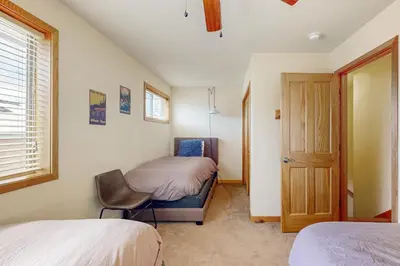 a bedroom with two beds and a chair and a door at Cabin Sweet Cabin in Winter Park