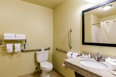 a bathroom with a toilet and a sink and a mirror at Cobblestone Inn & Suites-Kersey in Kersey