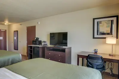 a hotel room with two beds and a desk and a television at Cobblestone Inn & Suites-Kersey in Kersey