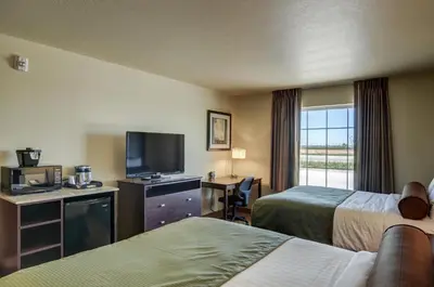 a hotel room with two beds and a flat screen tv at Cobblestone Inn & Suites-Kersey in Kersey