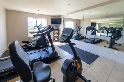 a gym with treadmills and ellipticals in front of a mirror at Cobblestone Inn and Suites - Eaton in Eaton