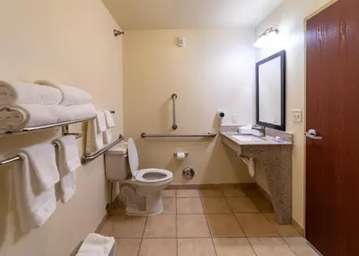 a bathroom with a toilet and a sink and a mirror at Cobblestone Inn and Suites - Eaton in Eaton