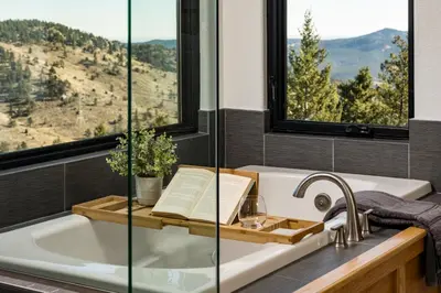 a bathroom with a bath tub with a book and a window at Stay in Evergreen - Denver Mountain Escape in Evergreen