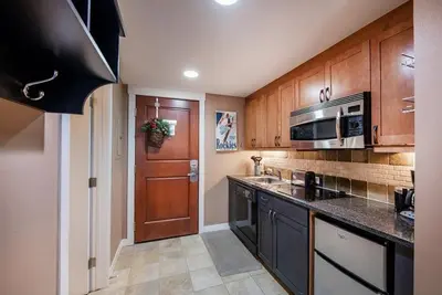 a kitchen with wooden cabinets and a microwave and a door at Premium Unit 4371- Fraser Crossing Founders Pointe condo in Winter Park