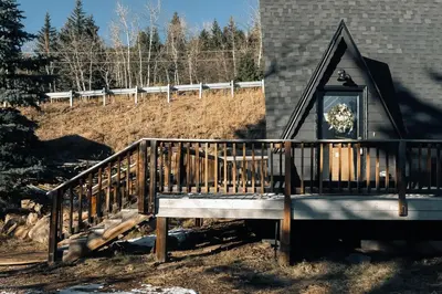 a porch with a clock on the side of a house at Modern A-Frame - Mountain Views - Evergreen in Evergreen