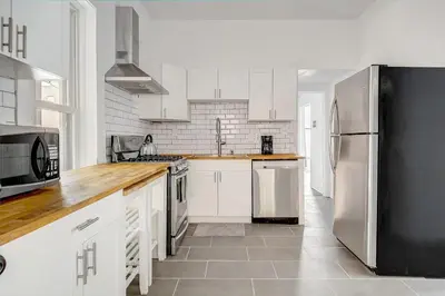a kitchen with white cabinets and a stainless steel refrigerator at Stiles Historical Estate - 26th St in Denver