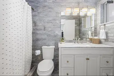 a bathroom with a toilet and a sink and a mirror at Sunny Beach House of Olde Town Arvada in Arvada