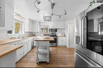a kitchen with white cabinets and a large refrigerator at Sunny Beach House of Olde Town Arvada in Arvada