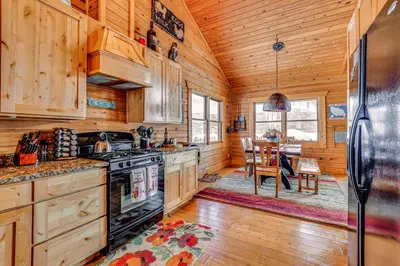 a kitchen with wooden cabinets and a dining room at Private Hot Tub Mtn-View Grand Lake Cabin! in Grand Lake