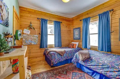 two beds in a room with wooden walls at Private Hot Tub Mtn-View Grand Lake Cabin! in Grand Lake