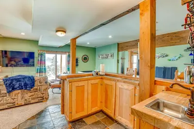 a kitchen with green walls and wooden cabinets and a sink at Private Hot Tub Mtn-View Grand Lake Cabin! in Grand Lake