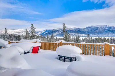 a deck covered in snow with mountains in the background at Private Hot Tub Mtn-View Grand Lake Cabin! in Grand Lake