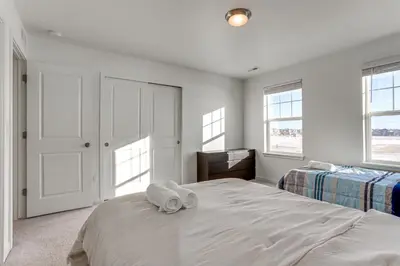 a white bedroom with two towels on a bed at 16 Mi to Denver Spacious Commerce City Home! in Commerce City