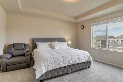 a bedroom with a bed and a chair and a window at 17 Mi to Downtown Denver Modern Aurora Home! in Aurora